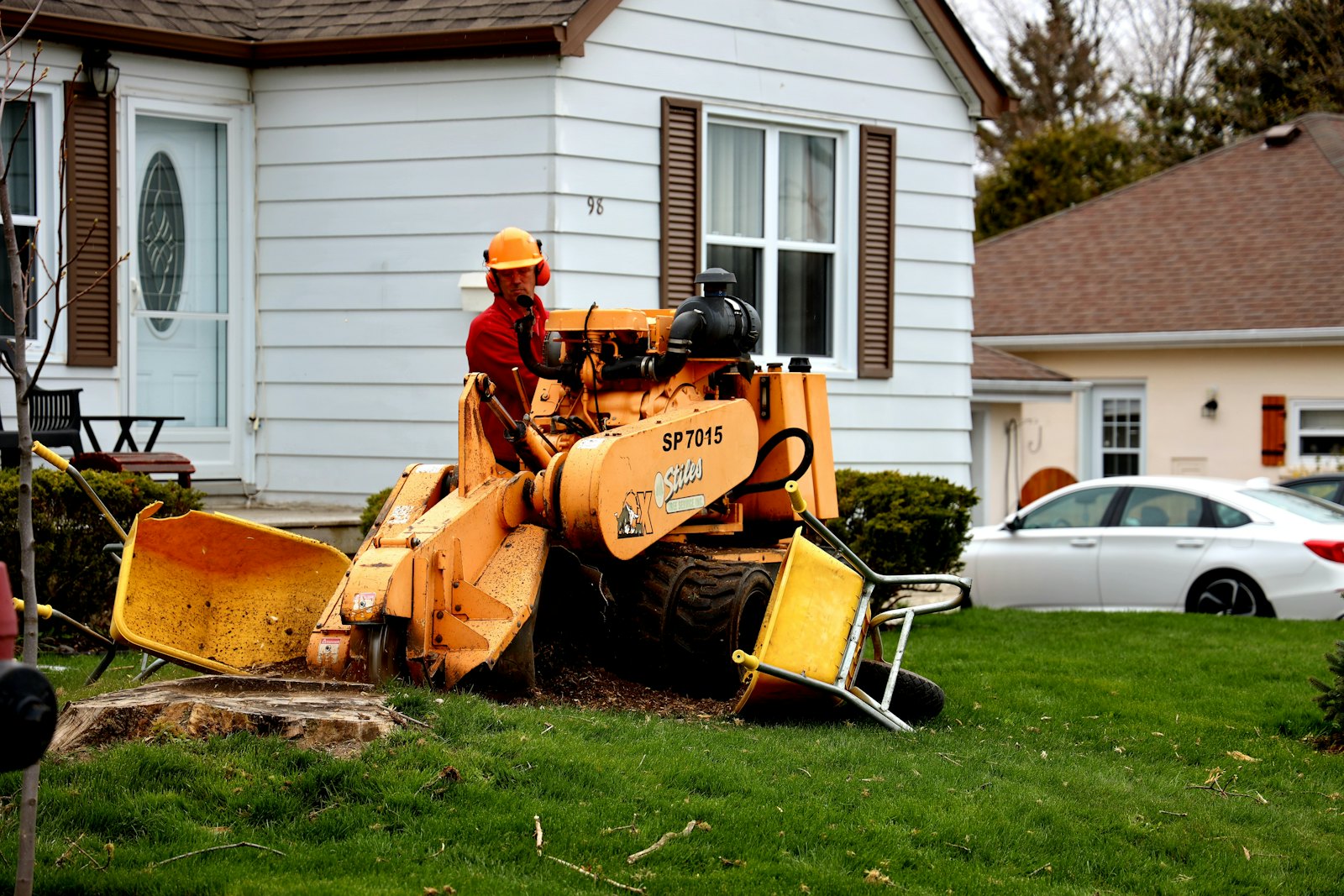Orange stump grinder grinding a tree stump below the lawn in a residential front yard