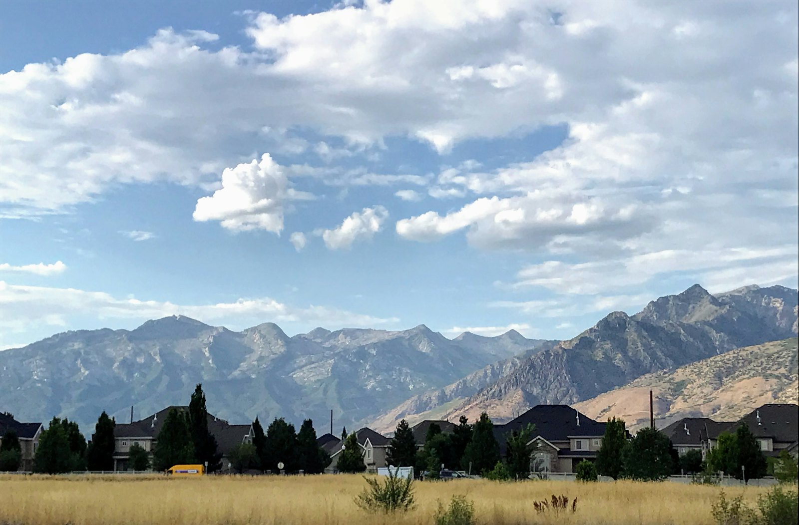 Open grass field and homes below the Wasatch Mountains in Davis County, Utah